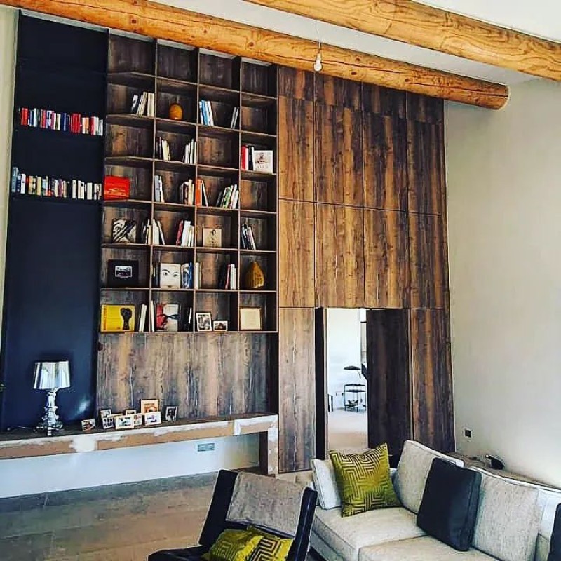 Pose d'une bibliothèque grandiose sur mesure à Gordes dans le Lubéron tout en bois foncé vieillie avec passage de porte caché.